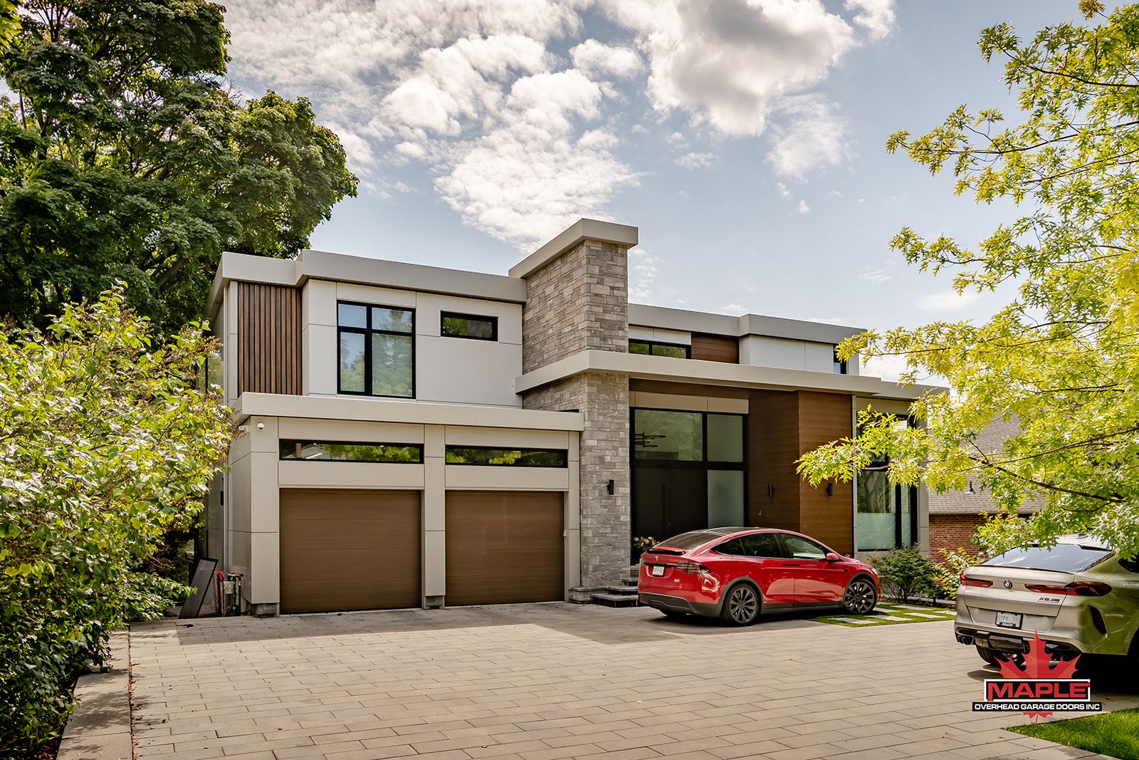 A red car is parked in front of a modern house.