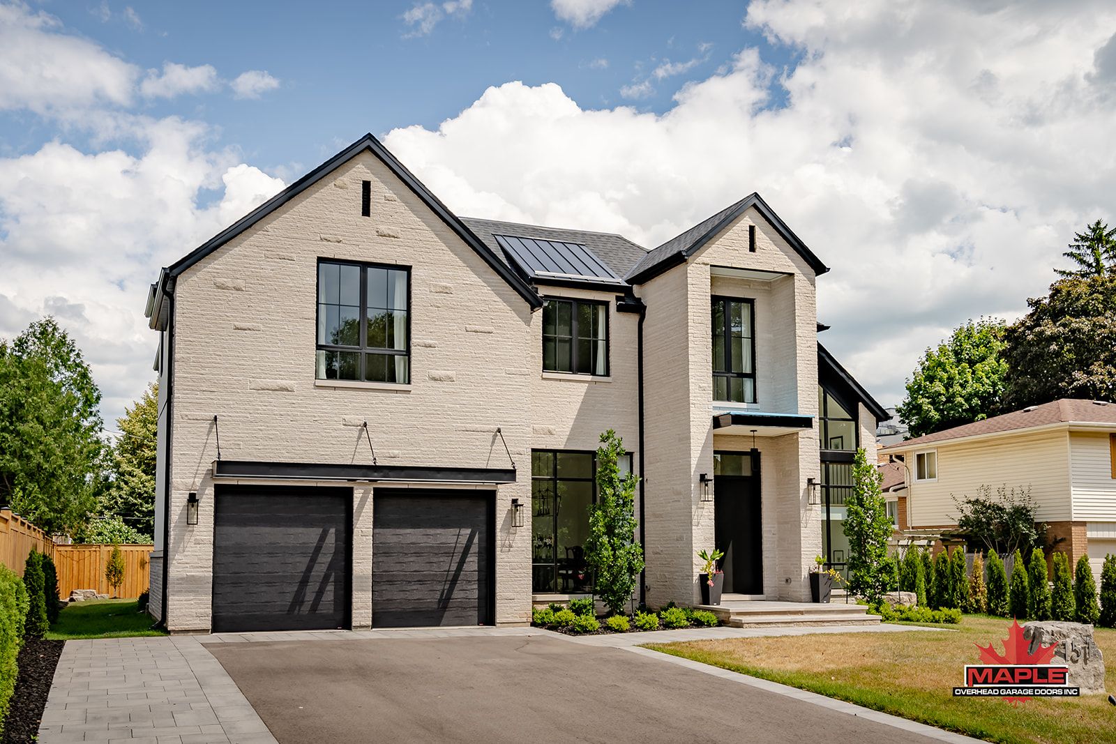 A large white brick house with a black garage door.