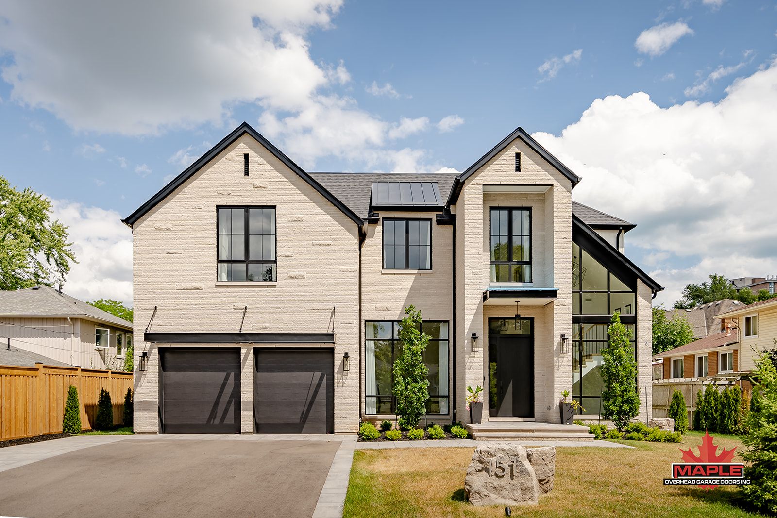 A large house with two garages and a sign in front of it.