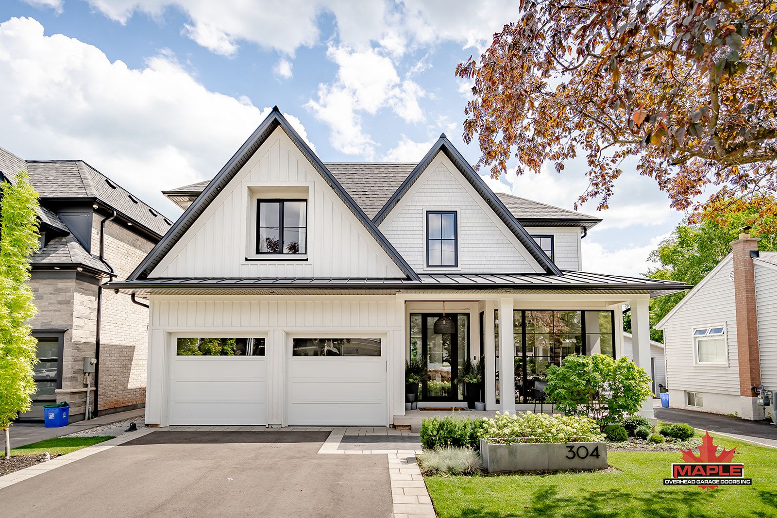 A white house with a black trim and a large garage is for sale.