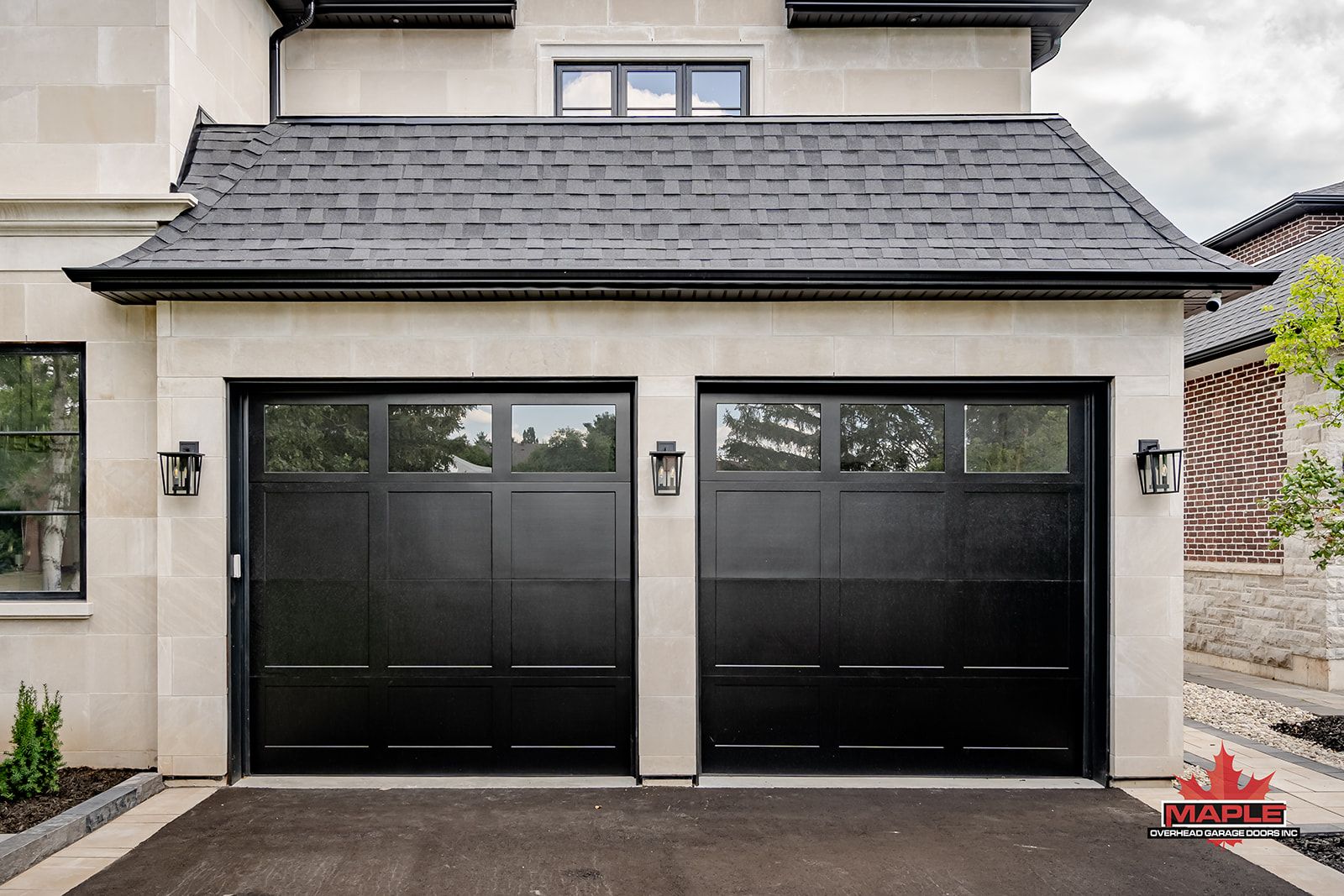 There are two black garage doors on the side of a house.
