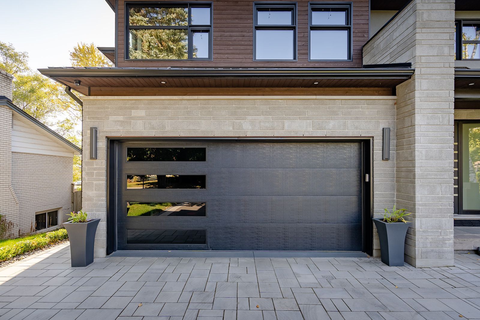 A black garage door is sitting in front of a brick house.
