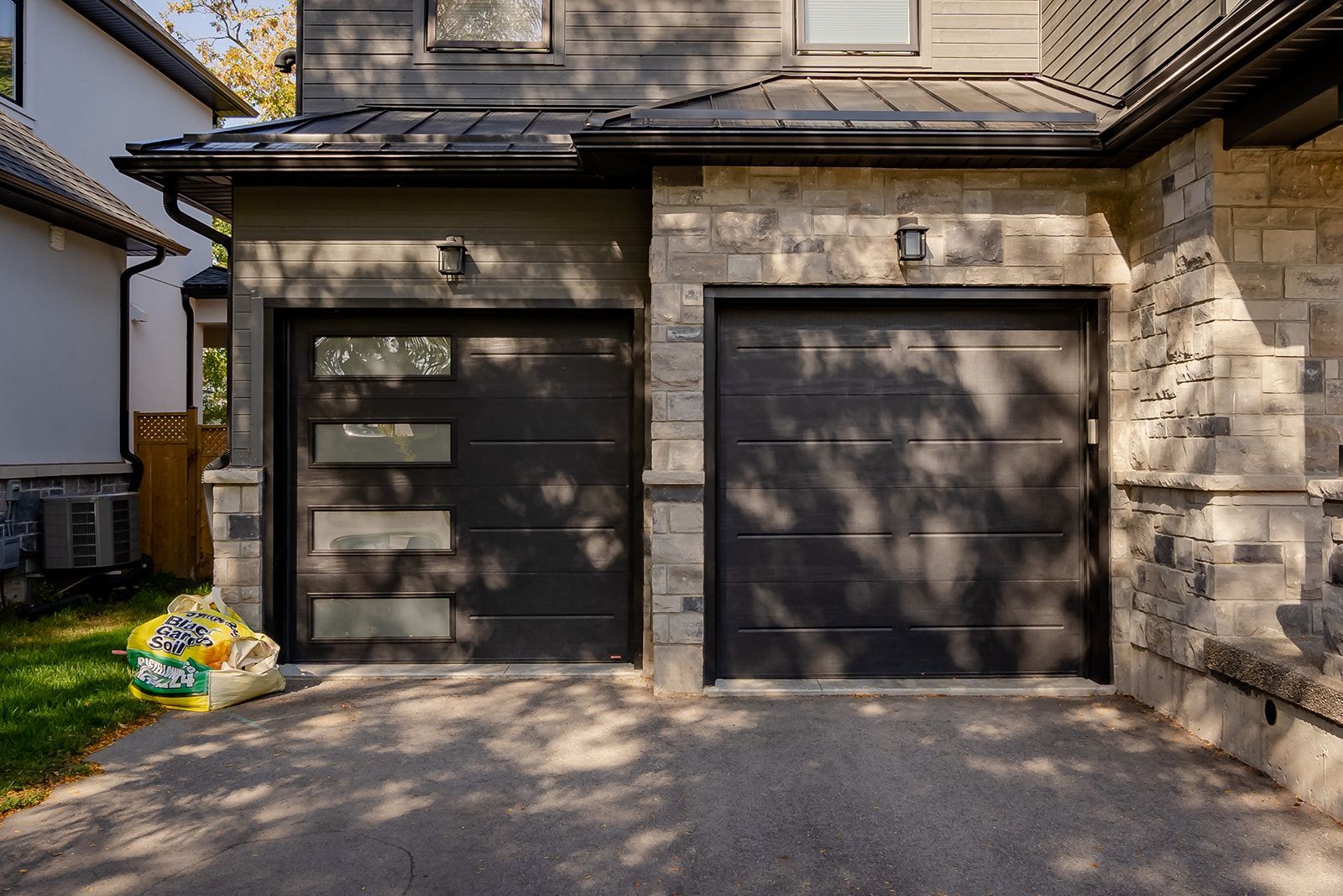 A black garage door is sitting in front of a brick house.