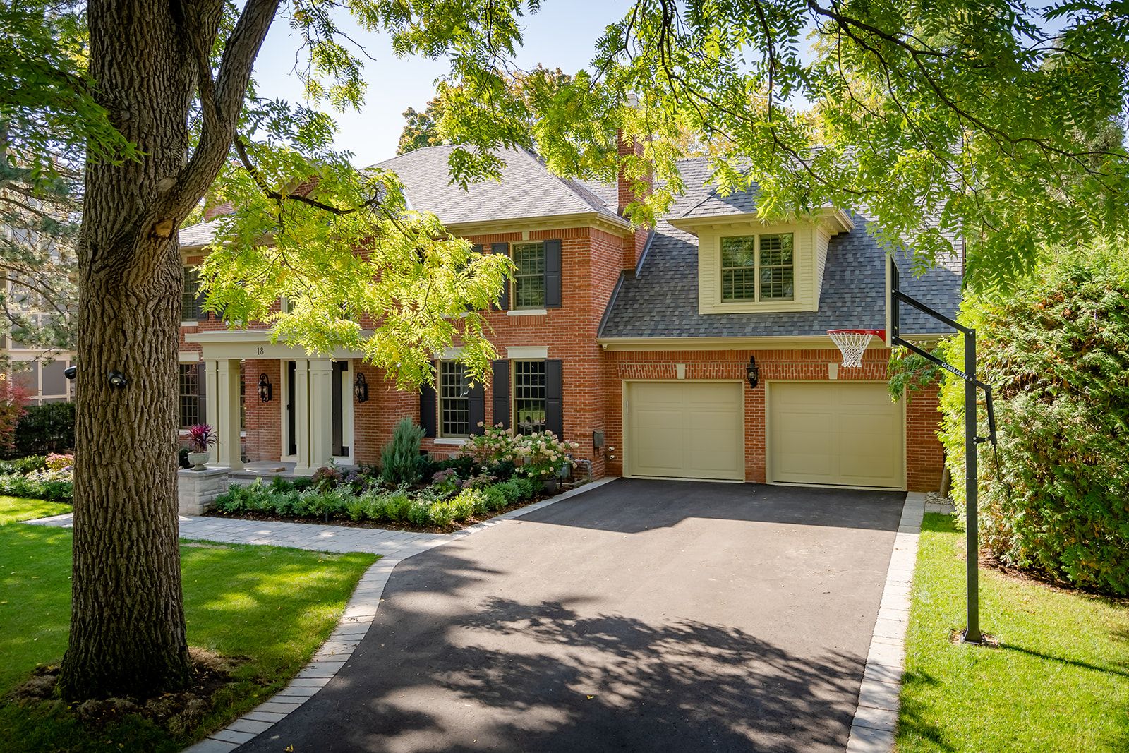 A brick house with two garage doors and a basketball hoop in front of it.