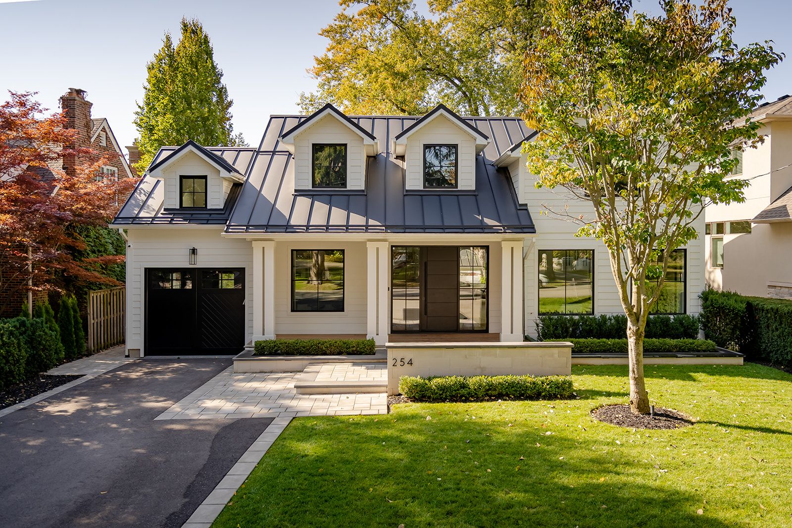 A white house with a black roof and a black garage door