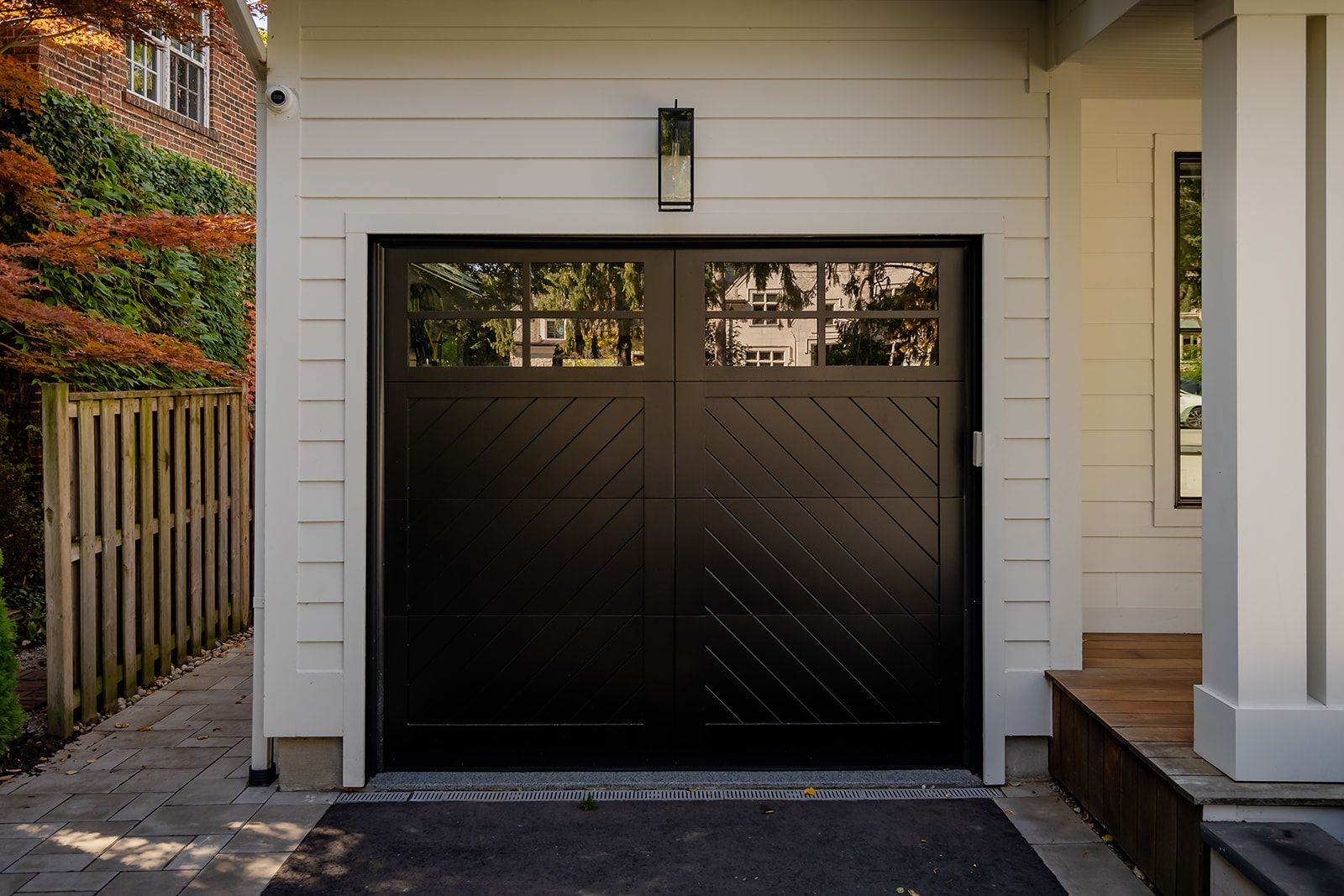 A black garage door is sitting in front of a white house.