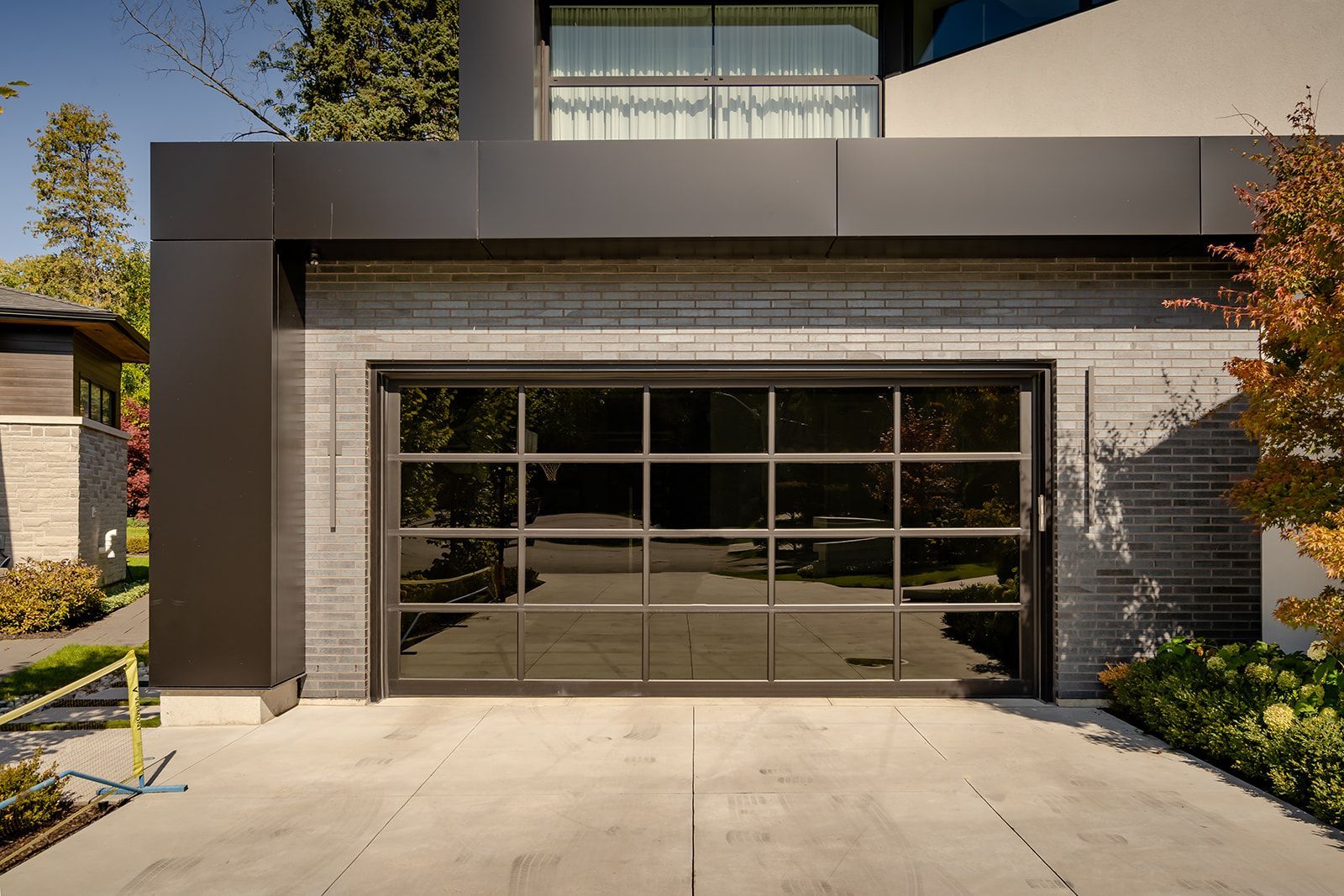 A modern garage door with a lot of windows is sitting in front of a house.