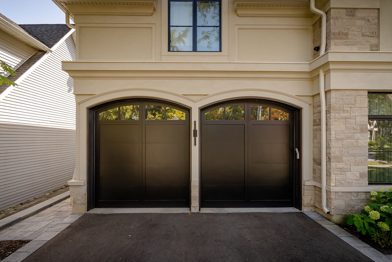 There are two garage doors on the side of a house.