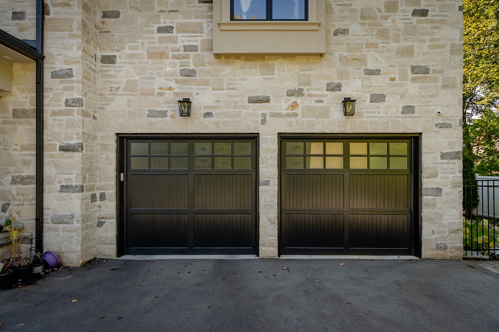 There are two garage doors on the side of a brick building.