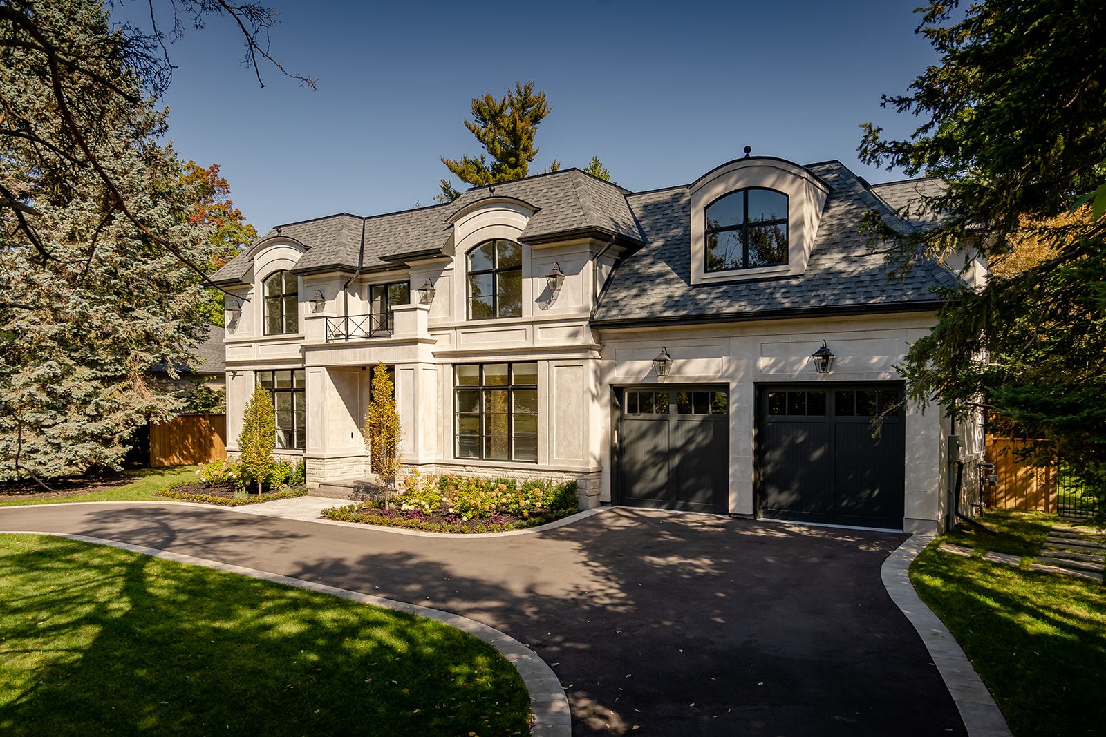 A large white house with a black garage door and a driveway.