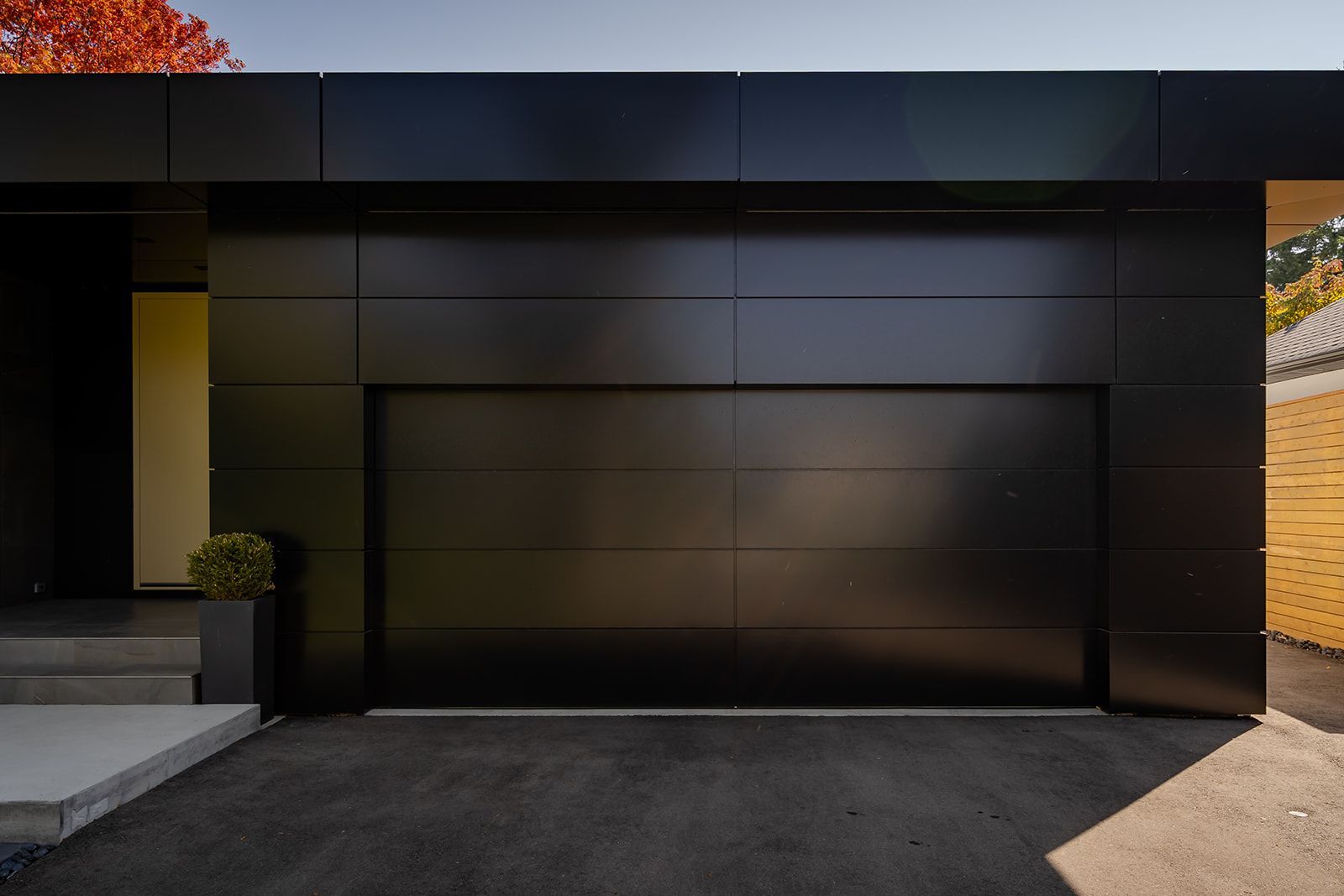 A black garage door is sitting in front of a house.