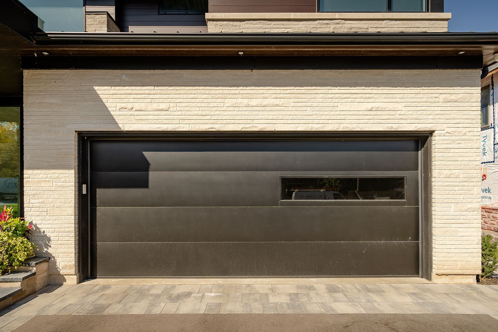A modern garage door with a window on the side of a house.