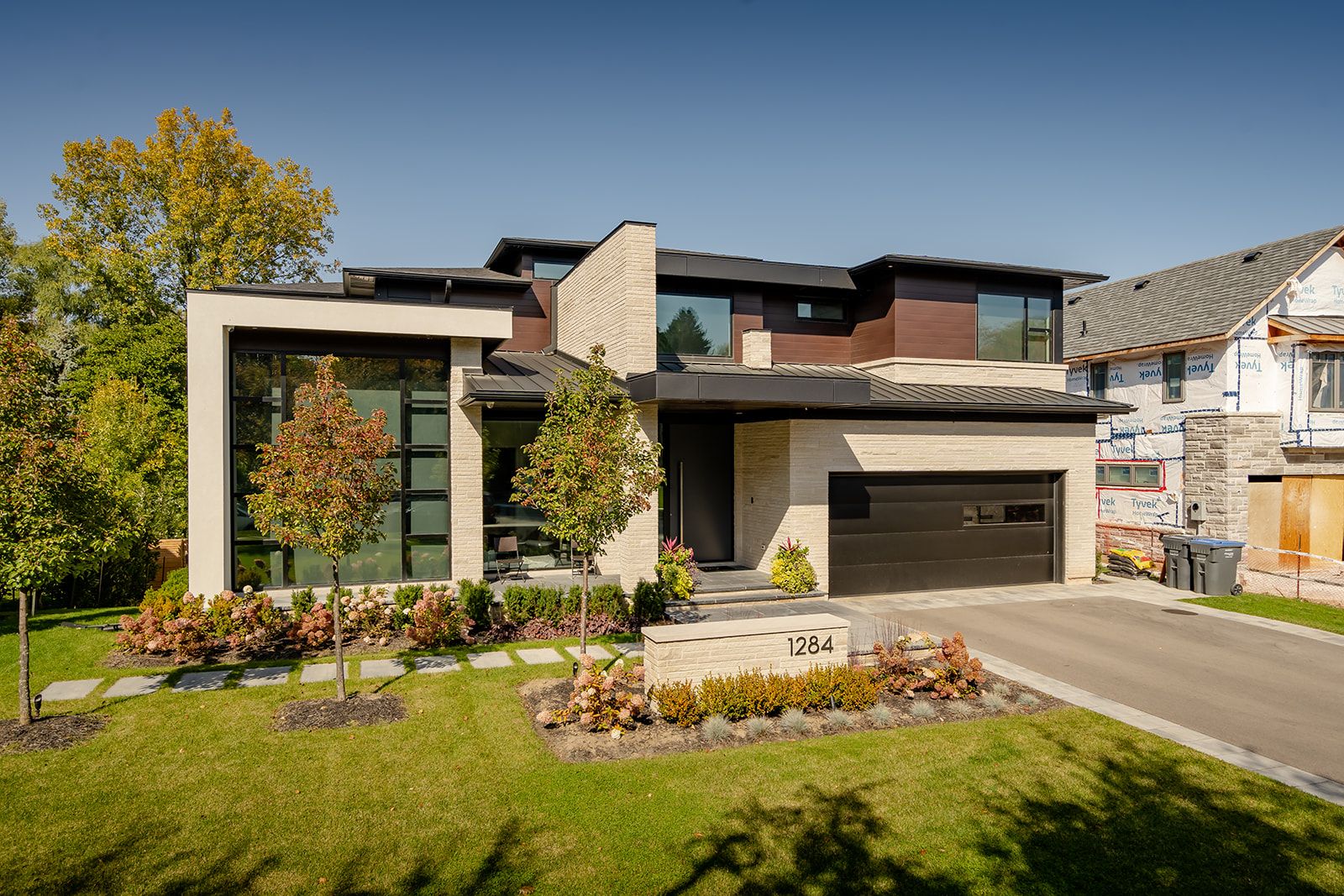 A large modern house is sitting on top of a lush green lawn.