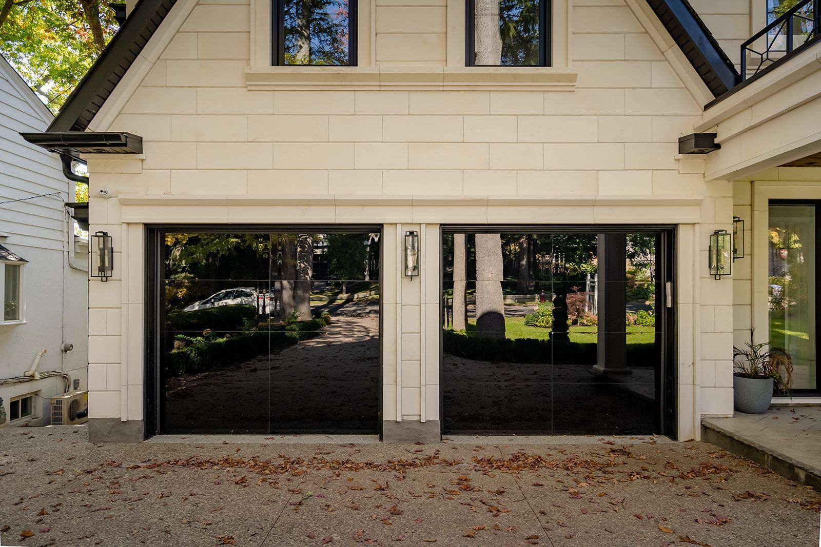 A white house with a black garage door and a driveway.