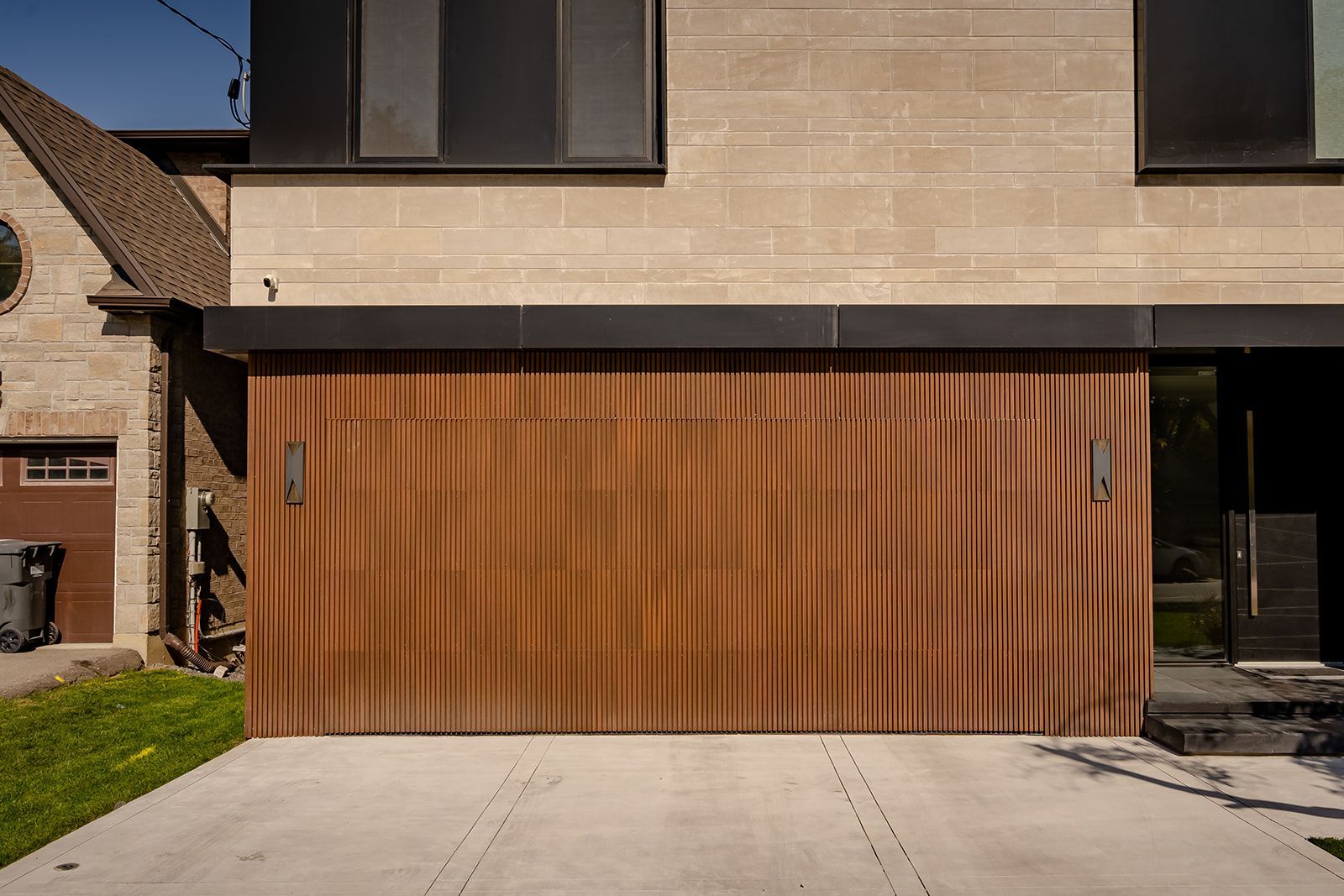A modern house with a wooden garage door and a concrete driveway.