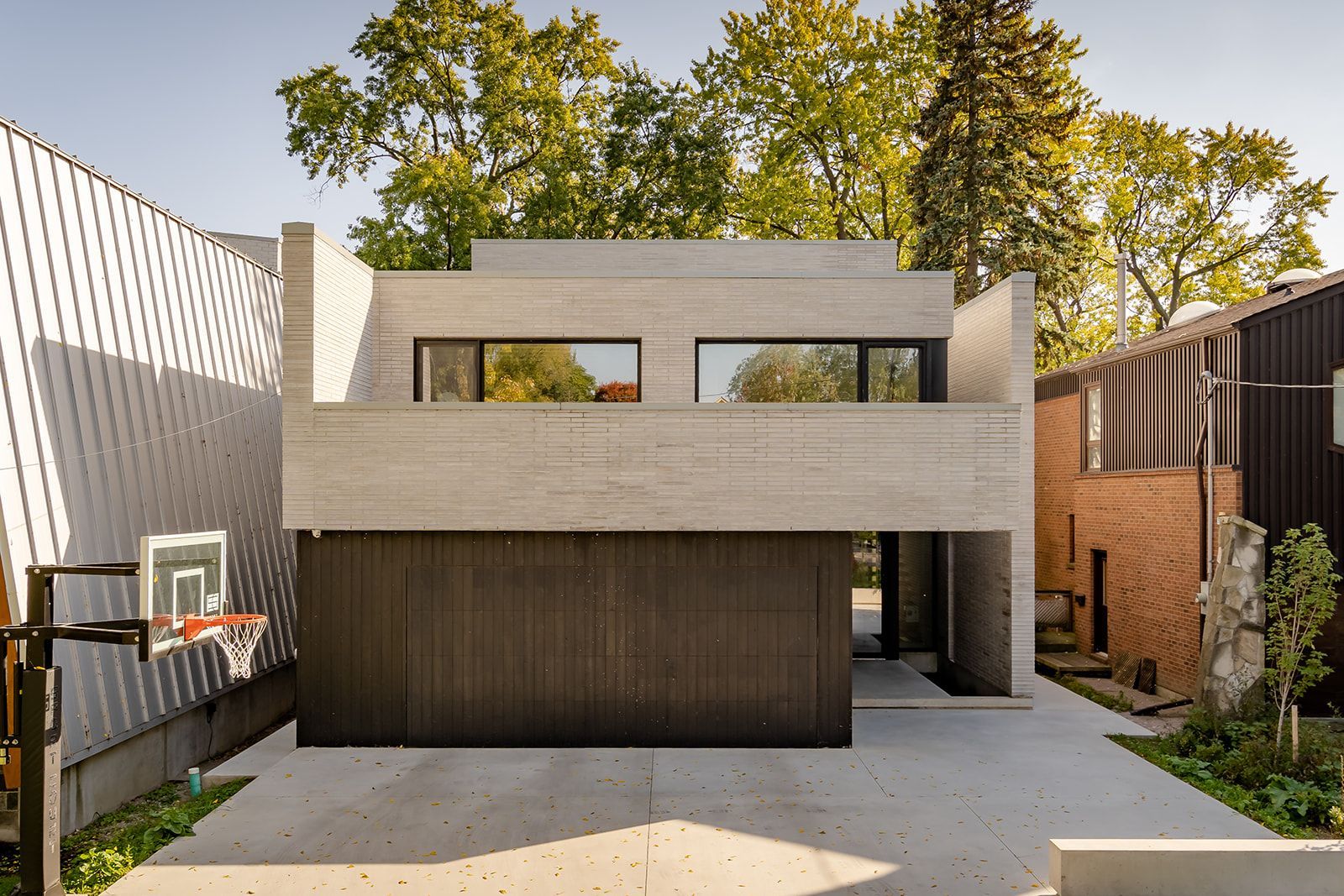 A house with a garage and a basketball hoop in front of it.