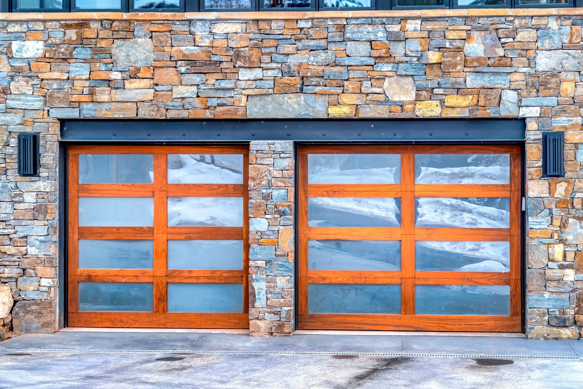 A pair of wooden garage doors on a stone building.