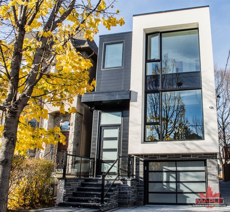 A black and white house with a tree in front of it