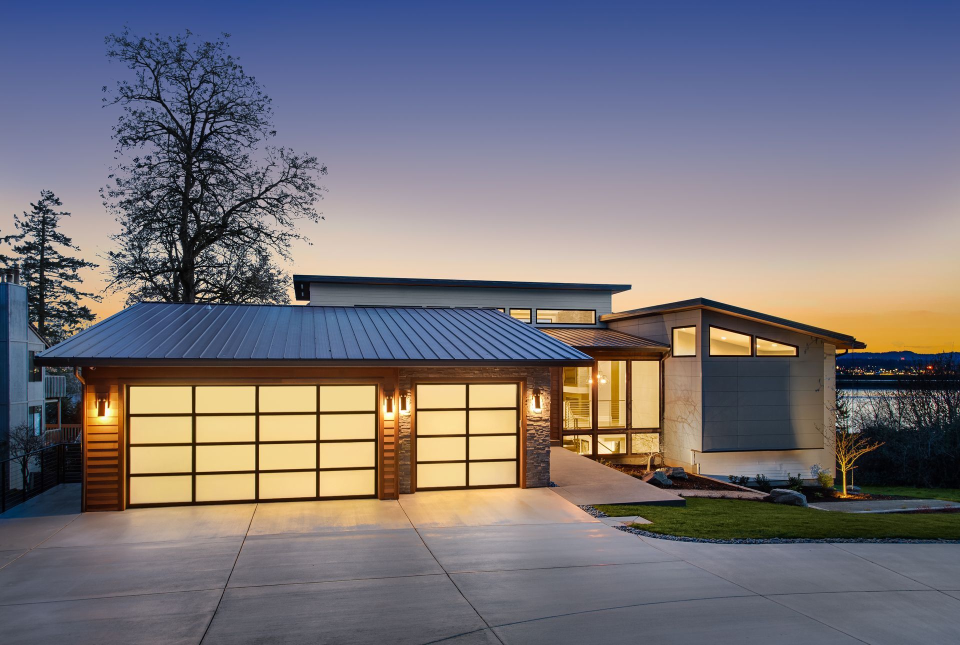 A modern house with a large garage door is lit up at night.