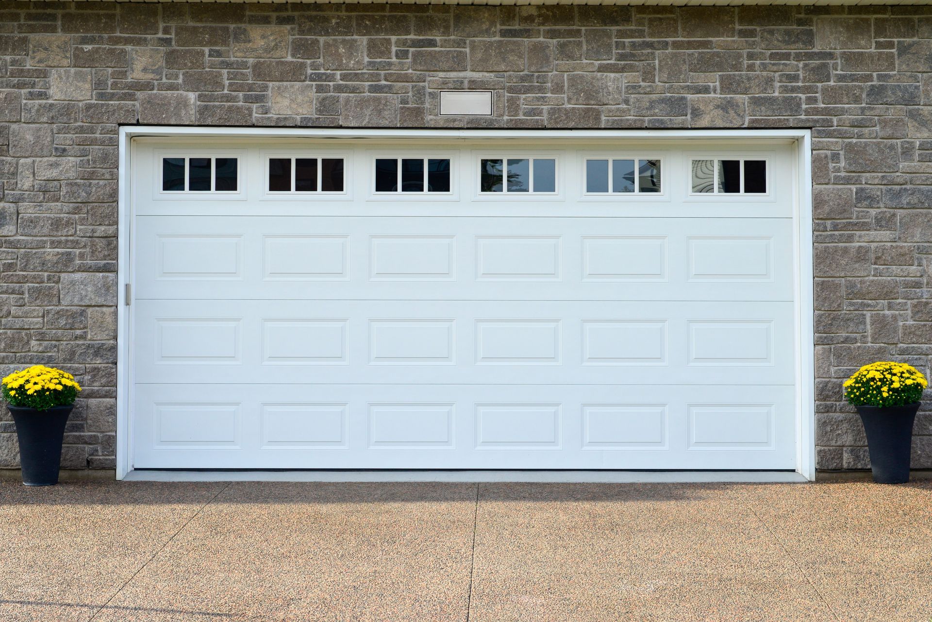 A white garage door is sitting in front of a brick wall.