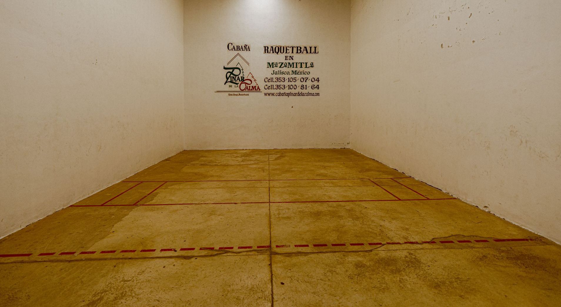 Una cancha de squash vacía con un cartel en la pared que dice squash