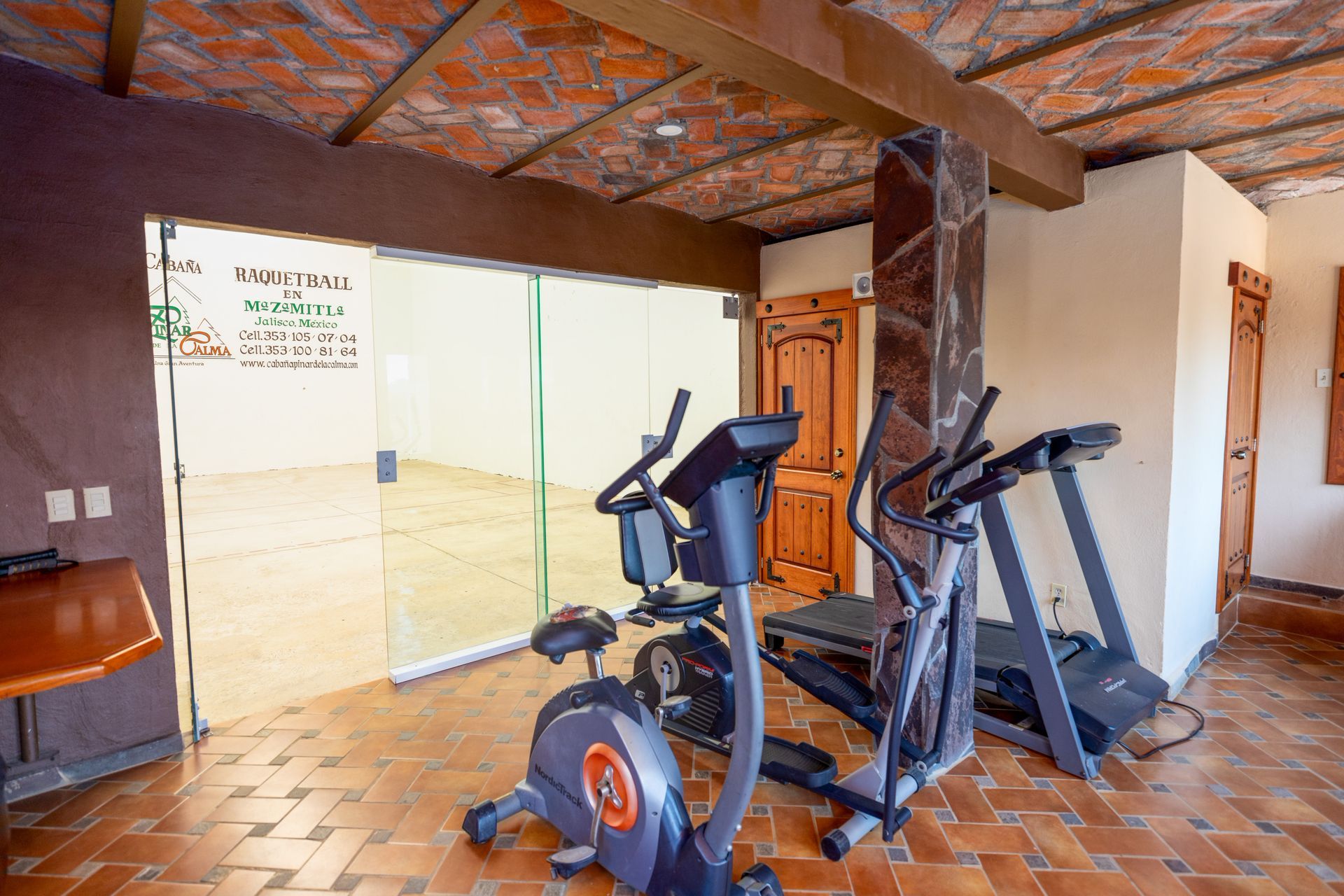 Un gimnasio con cinta de correr, bicicleta estática y máquina elíptica.