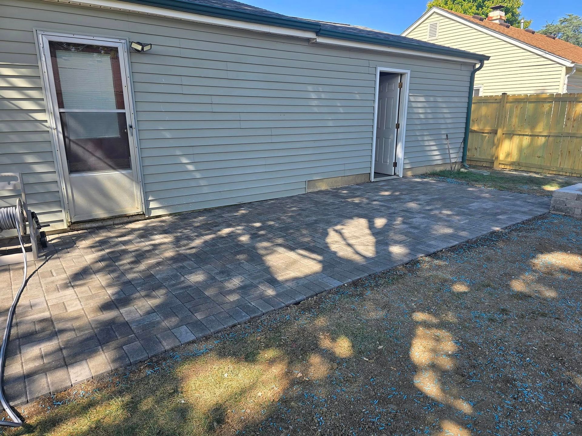 Brick patio against a light blue-gray building with two open doorways, set in a grassy yard.