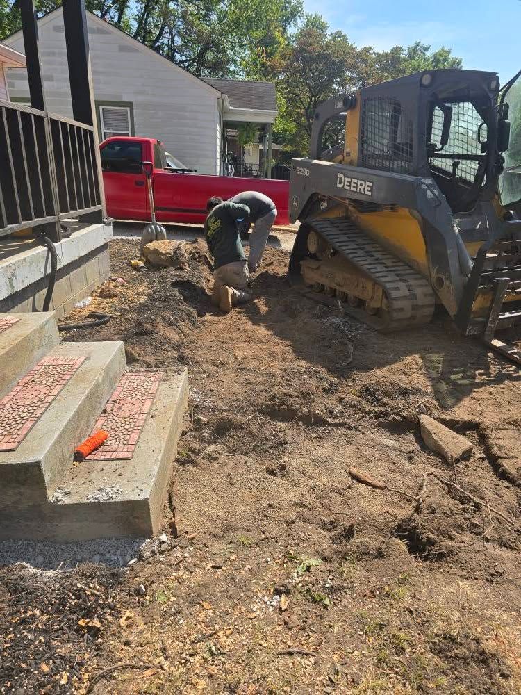 Construction site with workers, small excavator, and concrete steps.
