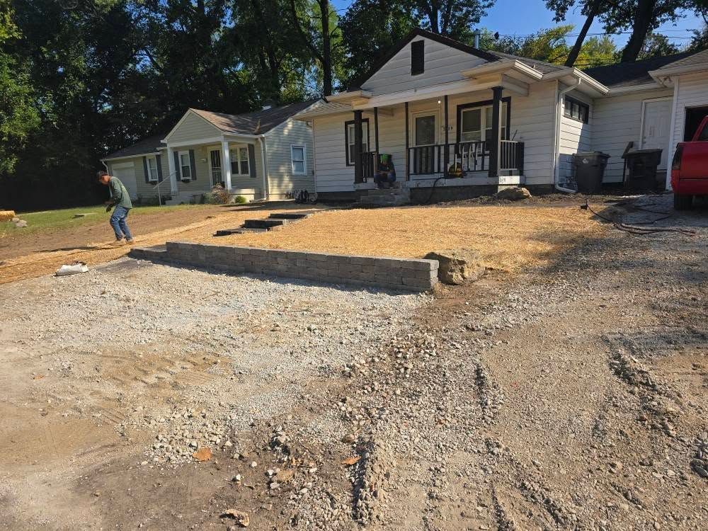 Construction site with two houses, gravel ground, and a worker near a concrete structure.