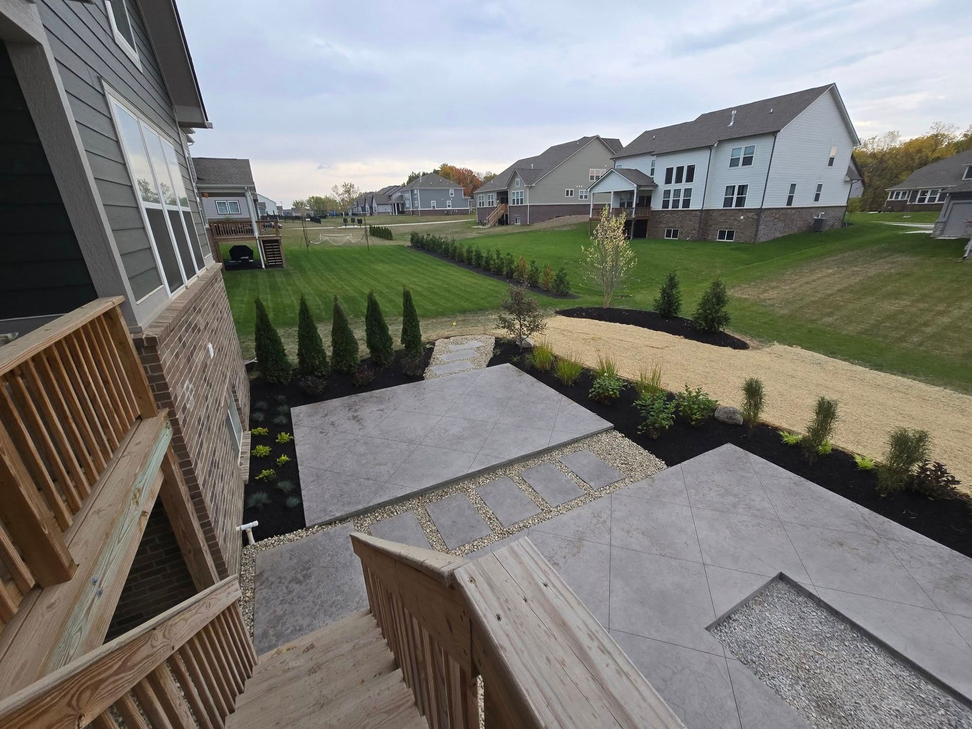 Backyard patio with stairs, landscaping, and views of neighborhood homes.