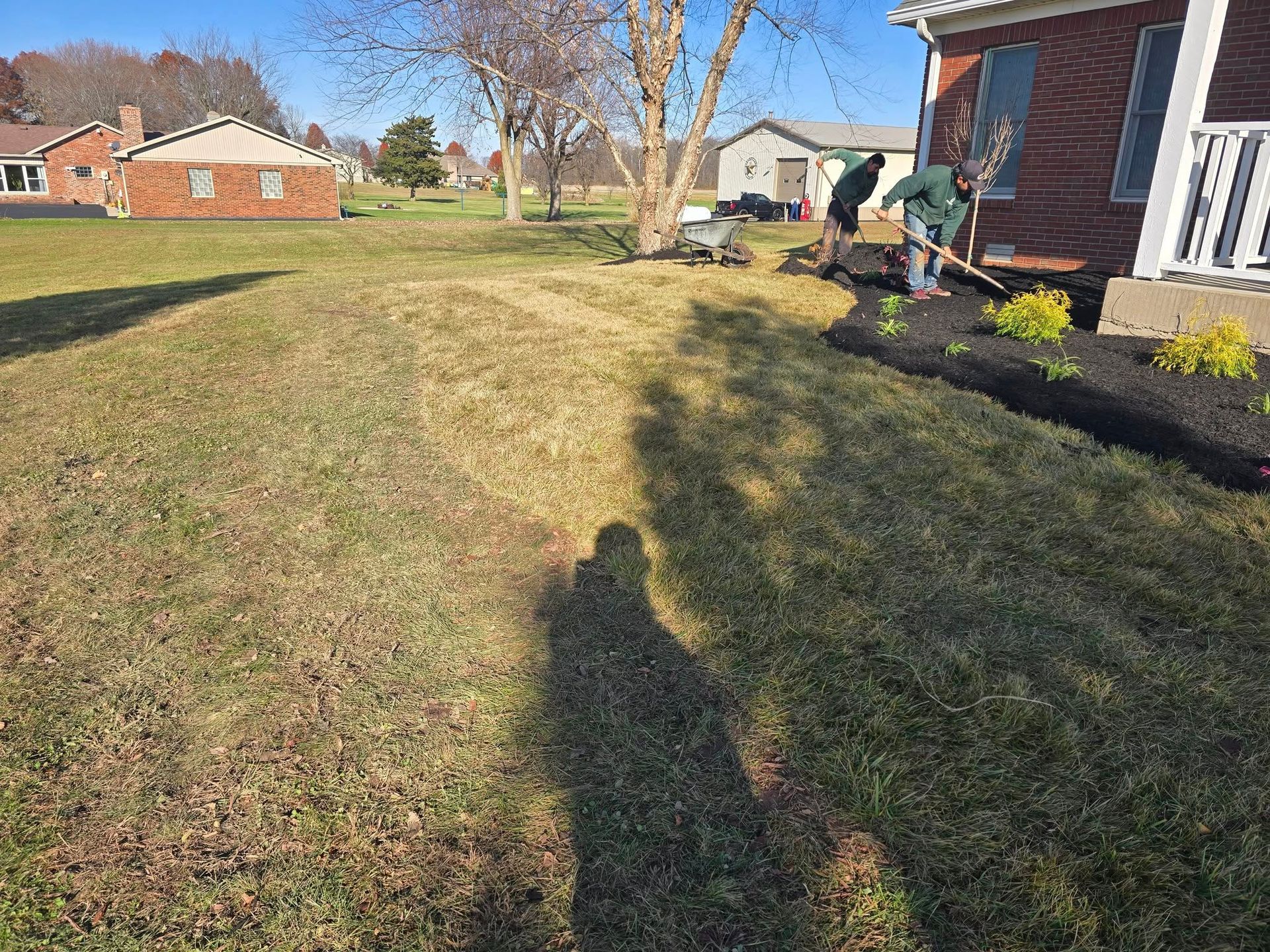 Yard with two people working near house; landscaping work.
