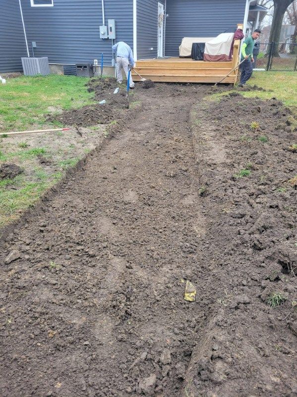 Workers digging a trench in a yard, leading towards a wooden deck.
