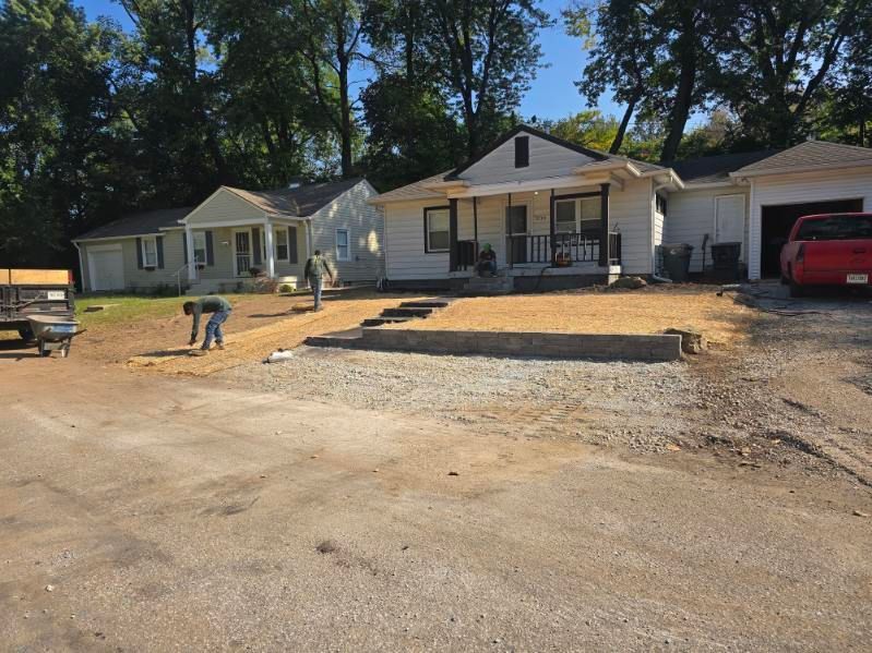 Two houses during construction with workers; gravel yard in front.