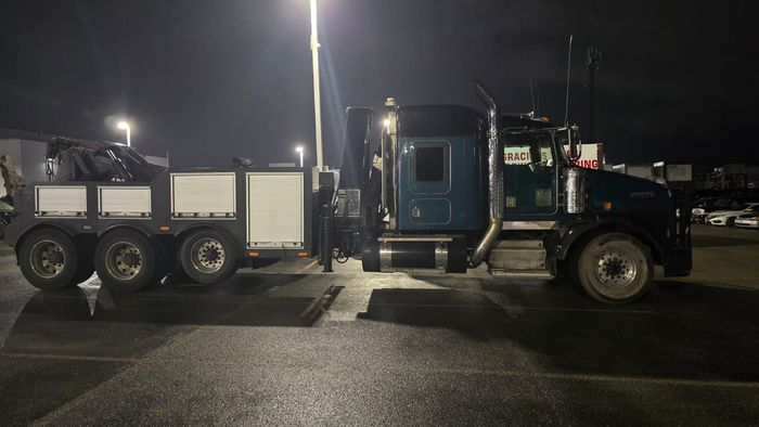 We work with safety in mind! Tow truck operator securing car to flatbed with chains