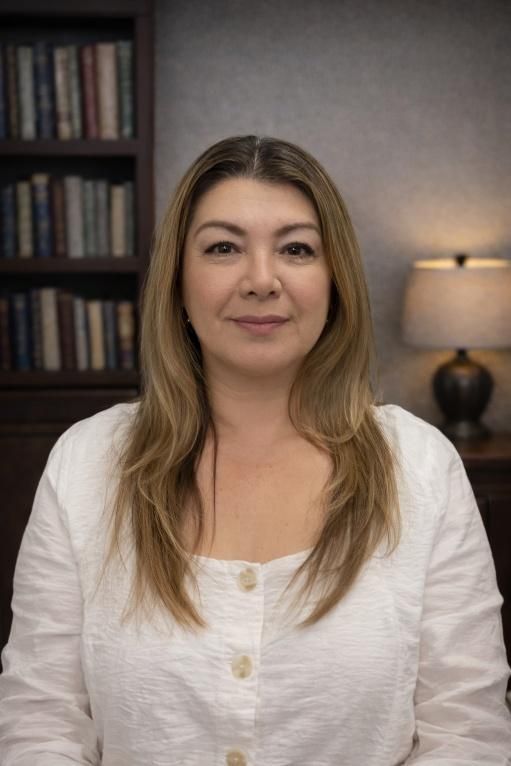 Woman in blue blazer, white shirt, looking at the viewer; cityscape in the background.