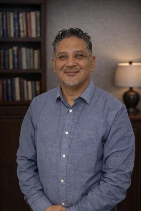 Woman in blue blazer, white shirt, looking at the viewer; cityscape in the background.