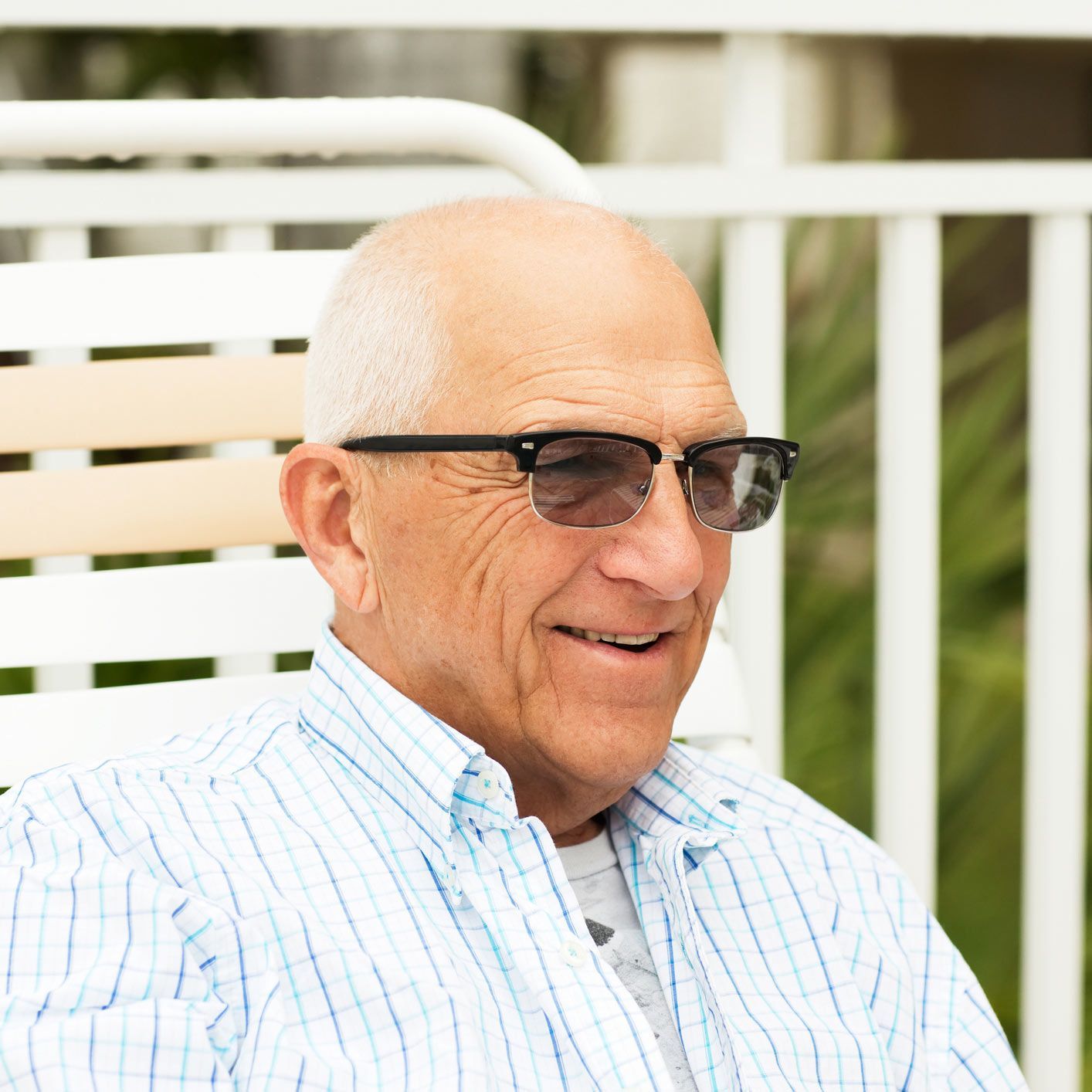 An older man wearing sunglasses is sitting in a chair