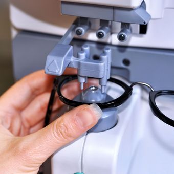 A person is holding a pair of glasses in front of a machine