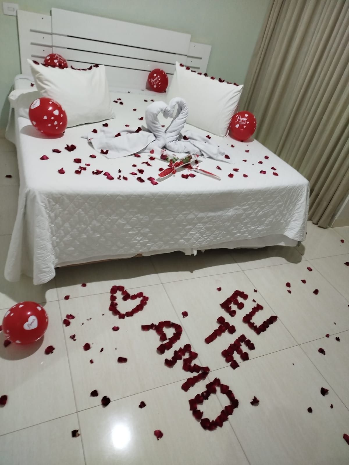 Quarto decorado para uma ocasião romântica, cama com pétalas de rosas, balões e