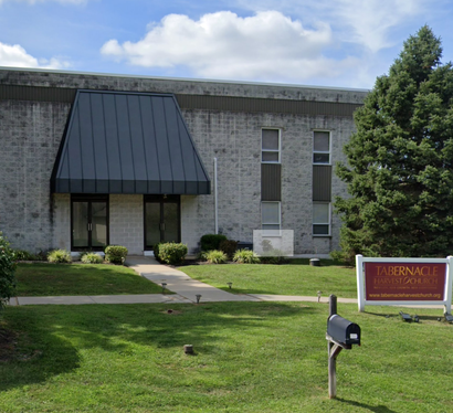 a large brick building with a metal roof and a mailbox in front of it