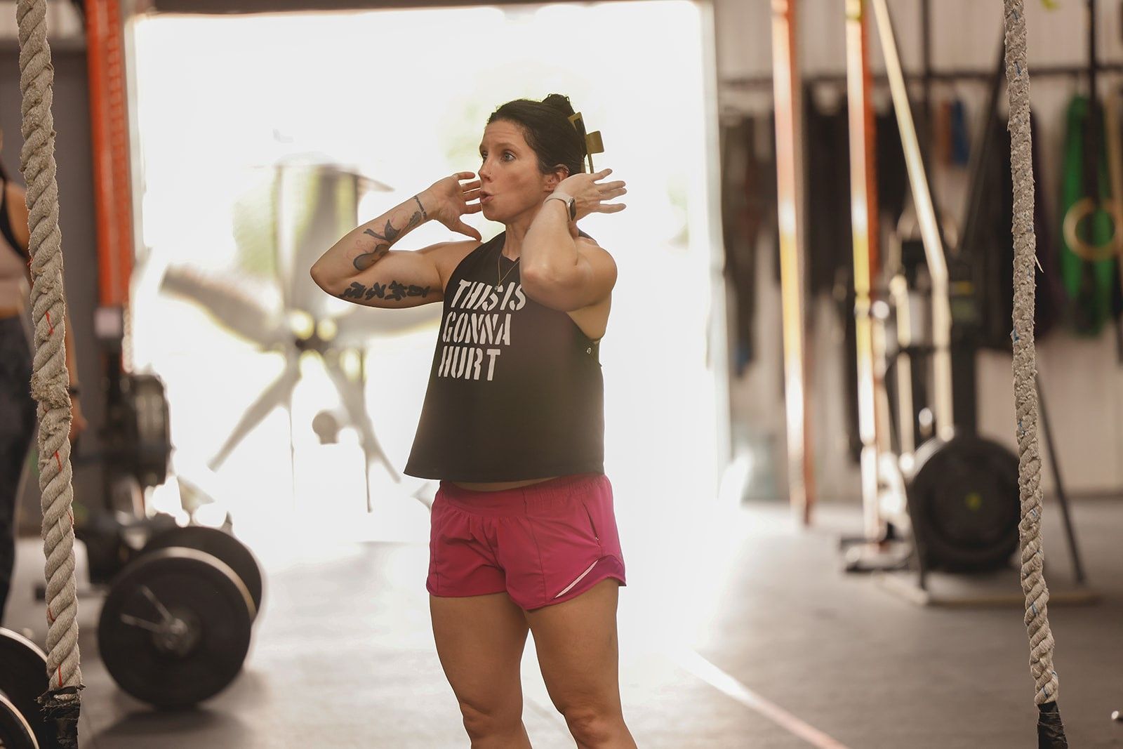 A woman is lifting a barbell over her head in a gym.