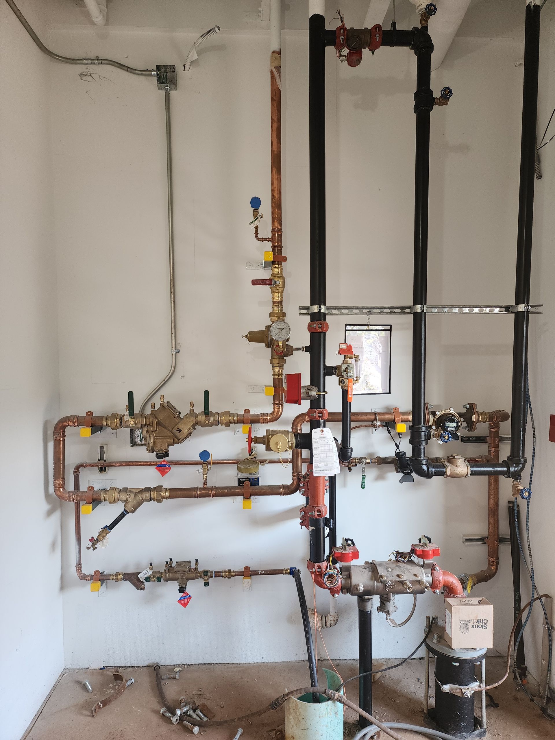 Wall-mounted plumbing and boiler pipes with valves and gauges in a utility room