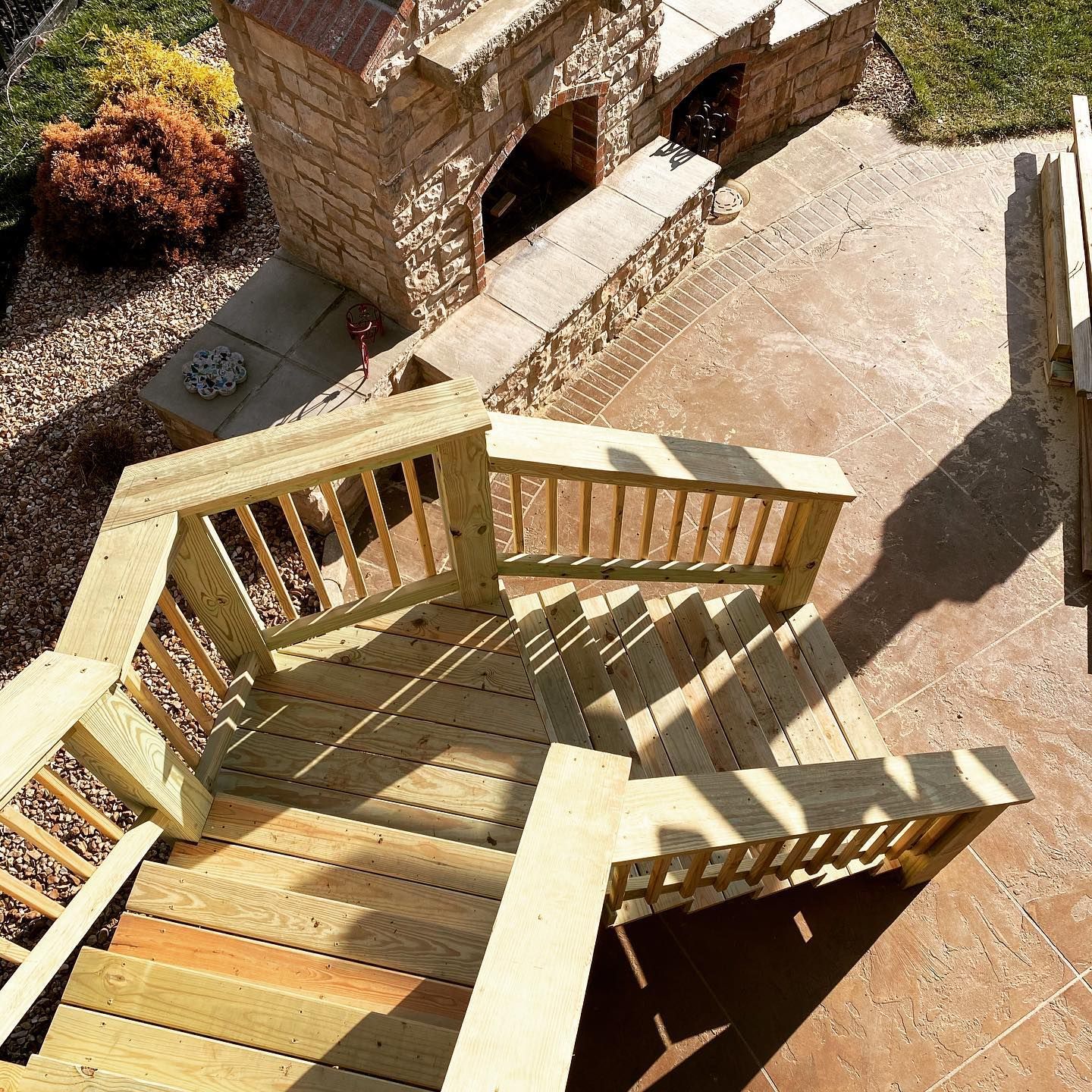 A wooden deck with stairs leading up to a stone fireplace