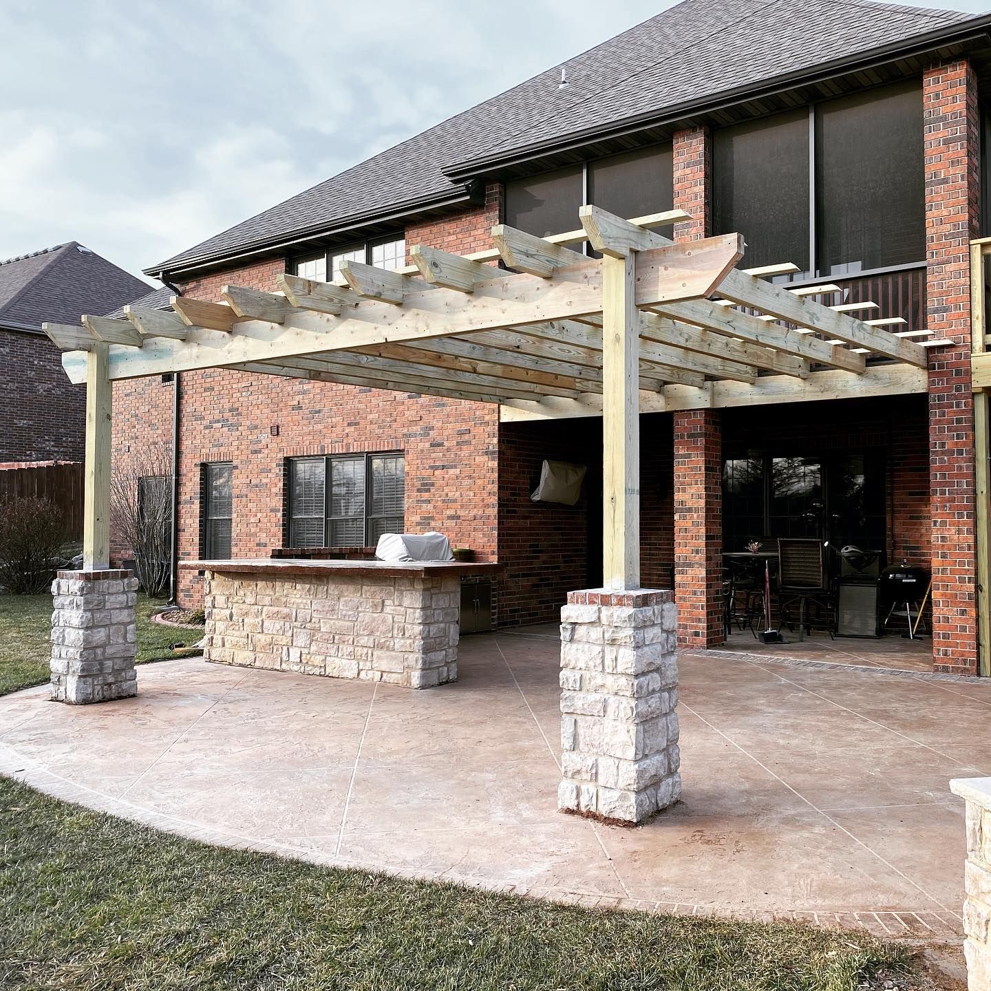 A brick house with a wooden pergola over a patio