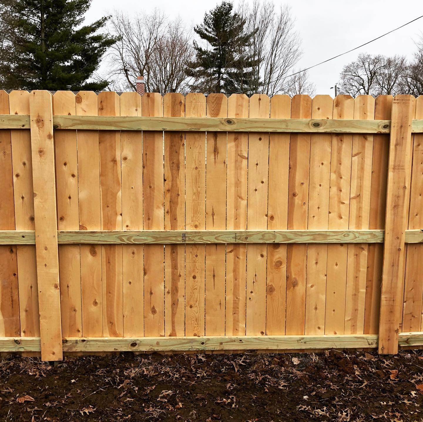 A close up of a wooden fence with trees in the background