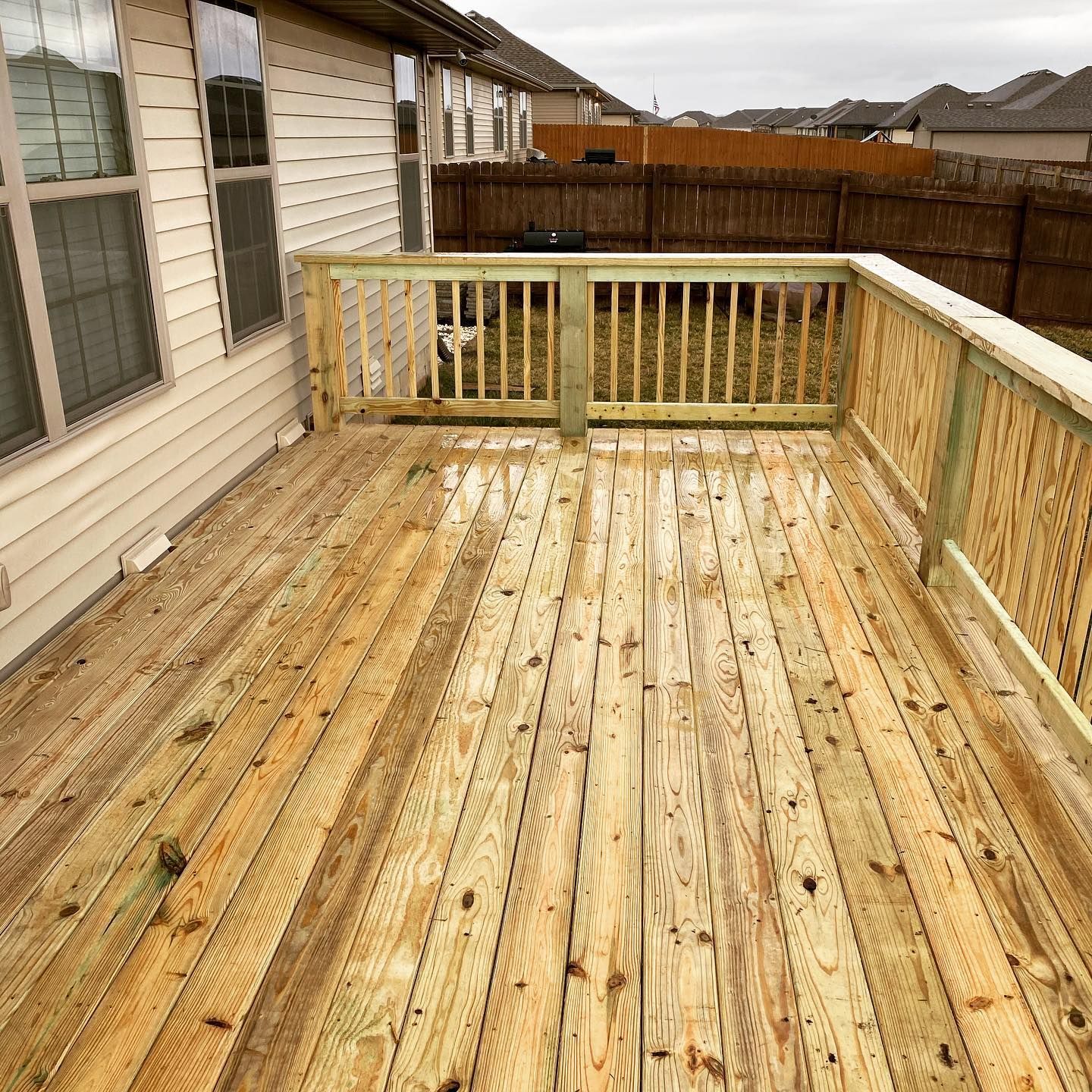 A wooden deck with a railing in front of a house.