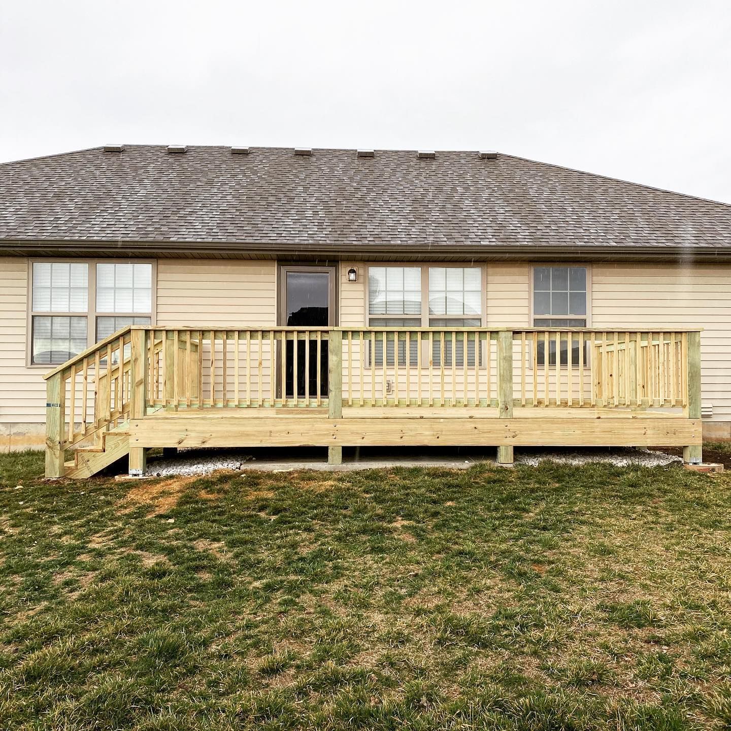 A house with a large wooden deck in front of it.