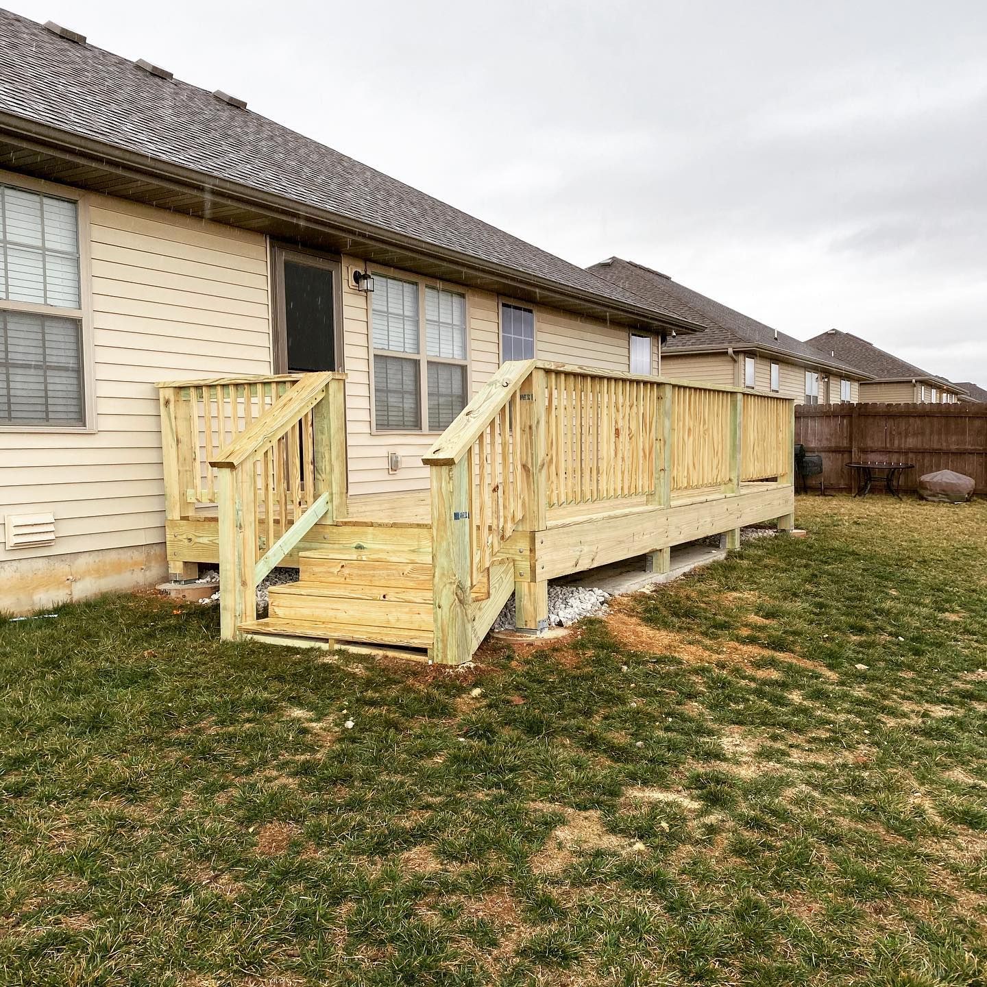A wooden deck with stairs is in the backyard of a house.