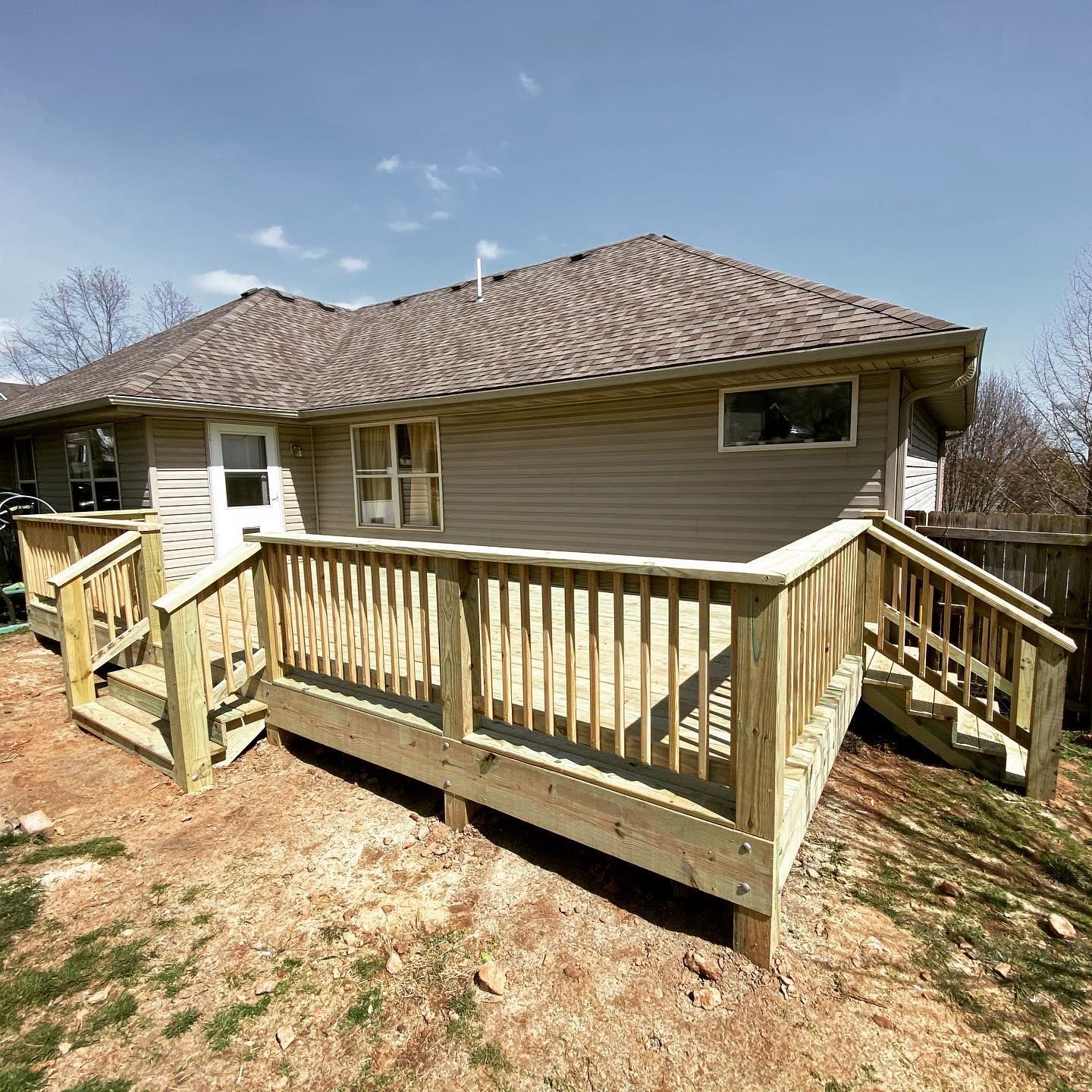 A wooden deck with stairs is in front of a house.