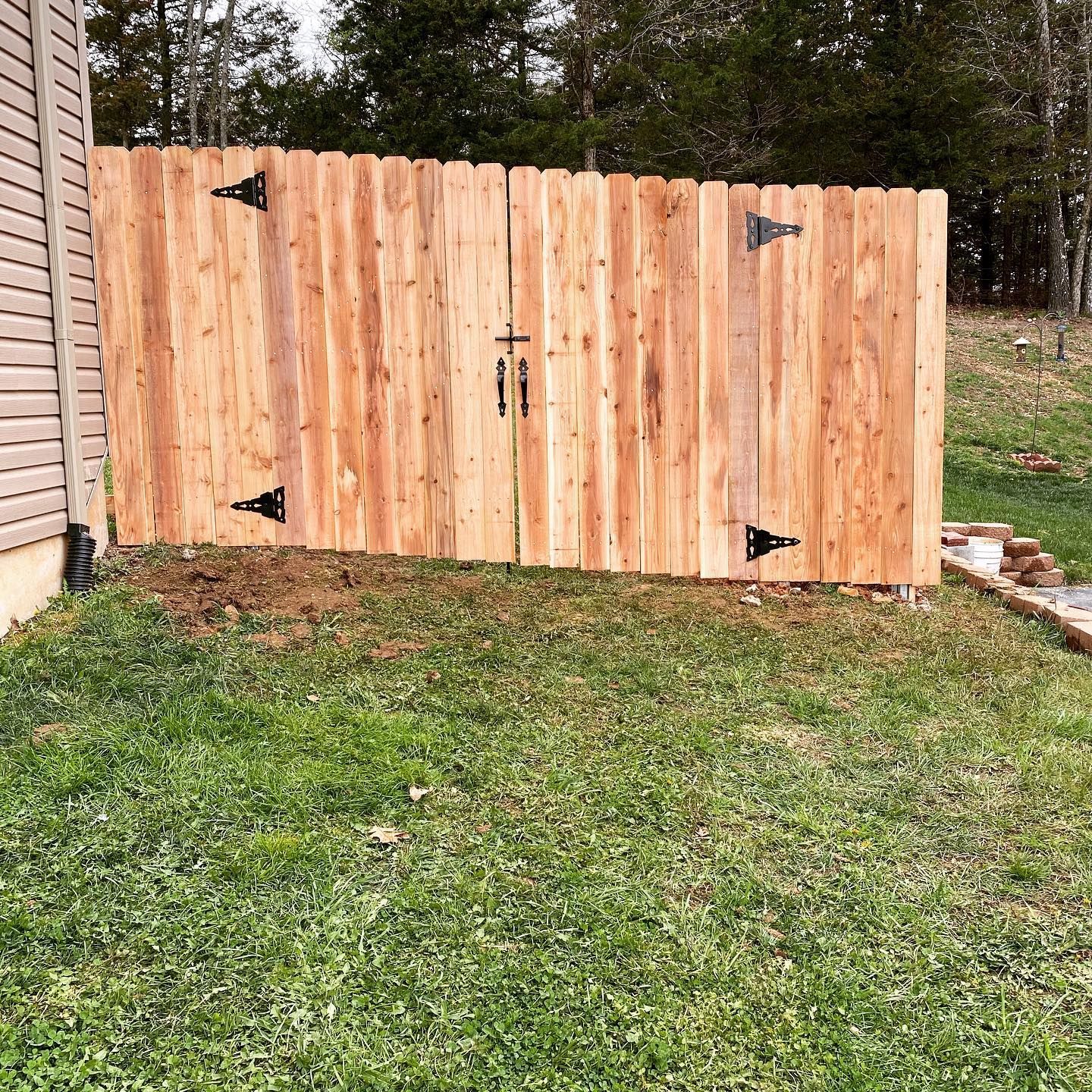 A wooden fence is sitting in the middle of a lush green field.